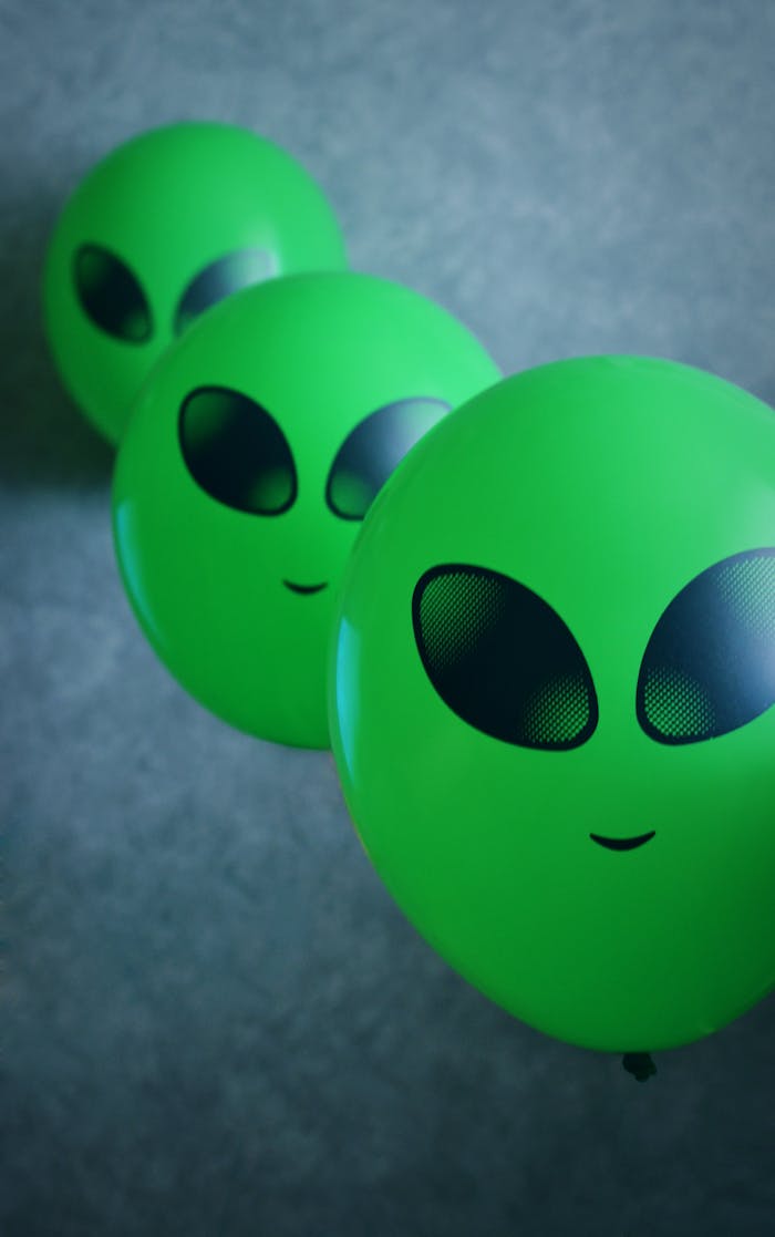 service-06 Playful green alien balloons floating in a vertical arrangement against a gray background.