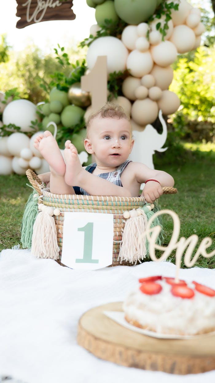 our-mission A cute baby enjoying their first birthday in a garden with balloons and cake.