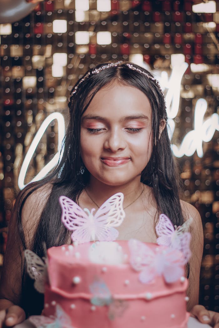 my-work-img Smiling girl celebrates her birthday with a pink butterfly cake indoors.