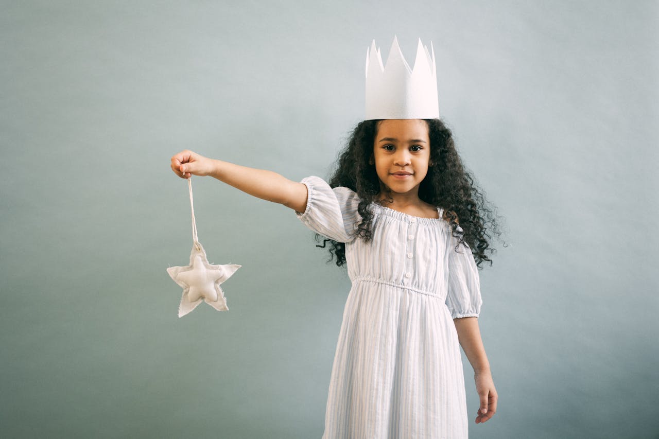 service-02 Adorable girl in a paper crown holding a star ornament, exuding fantasy and charm.